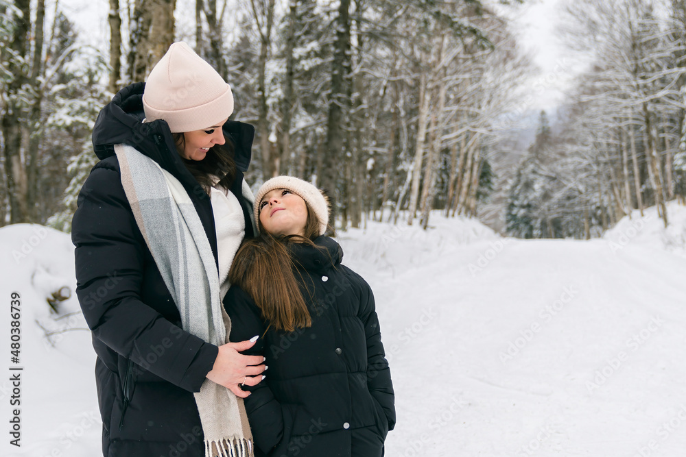 Handsome mother and his daughter are having fun outdoor in winter