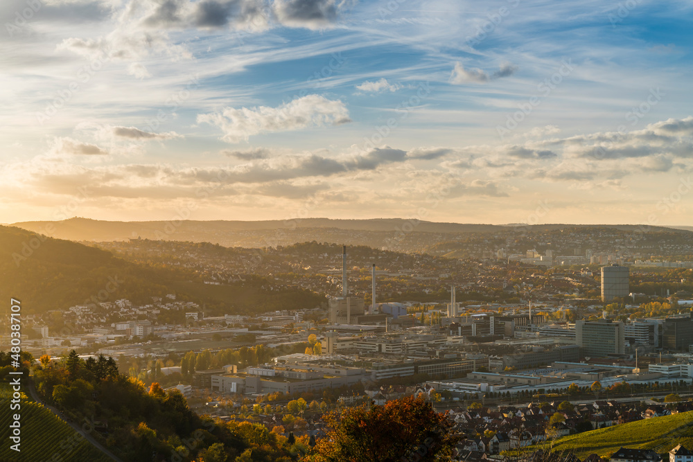 Germany, Stuttgart city panorama landscape view above industrial quarter and mountains, houses, streets at sunset in warm orange light