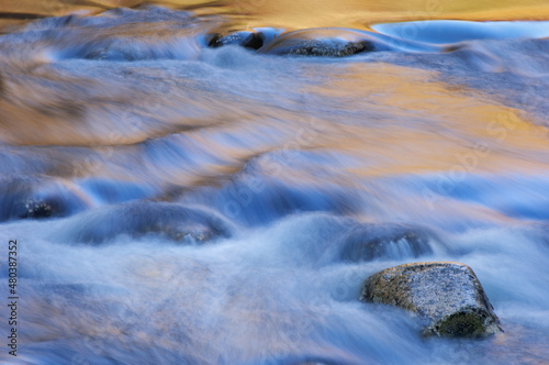 Spring landscape of the Little River captured with motion blur and illuminated by reflected color from sunlit foliage and blue sky overhead, Great Smoky Mountains National Park, Tennessee, USA