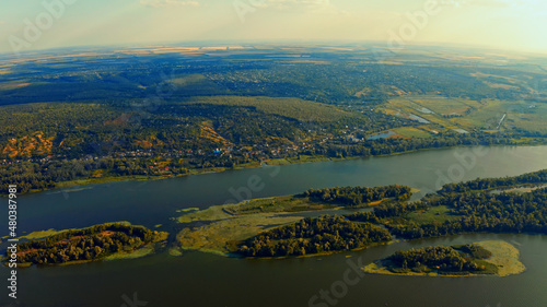 Photo from a drone of a beautiful summer landscape over the river. Beautiful summer landscape with a wide river and green coastline. Aerial photography of the suburban landscape. © Valua Vitaly