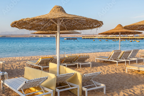 Hurghada  Egypt.  Buildings  swimming pools and a recreation area by the red sea. Umbrellas and sun loungers on an empty beach .Lounge chairs and Umbrellas early morning