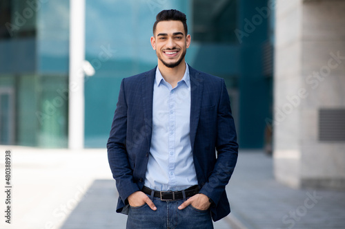 Handsome middle-eastern guy businessman posing next to office center