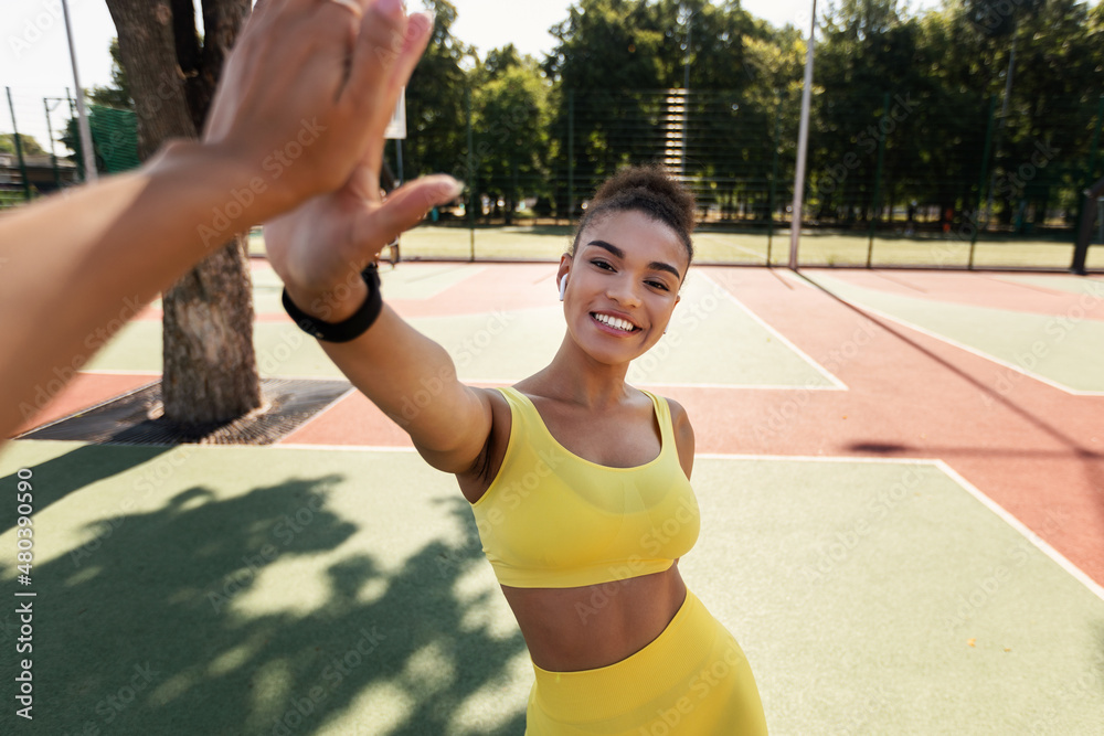 Obraz premium Sporty black woman in yellow sportswear giving high five