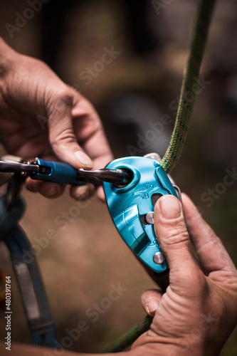 Man's hands operating a rock climbing belaying device © bizoo_n
