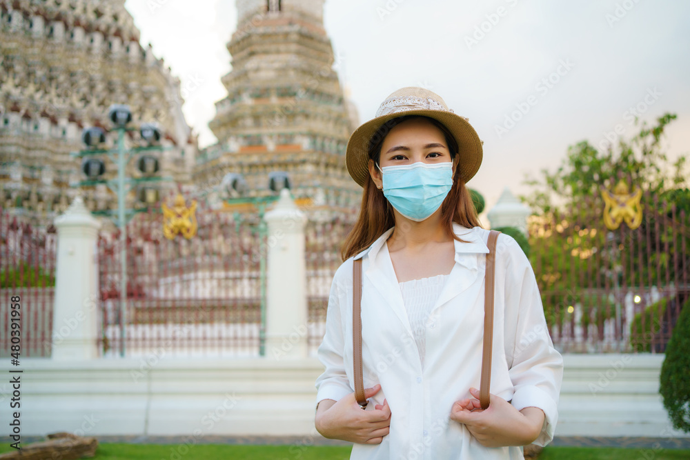 Asian woman tourist with mask is traveling at Wat Arun in Bangkok, Thailand.