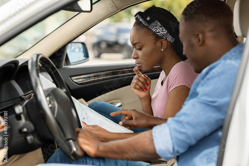 Afro american couple travelling by car, got lost, checking map
