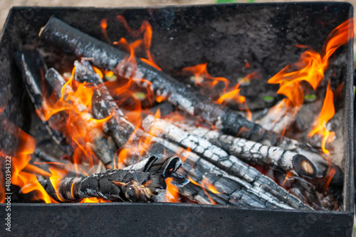 Closeup of a burning firewood for cooking BBQ in mangal outdoor. Ash and flame
