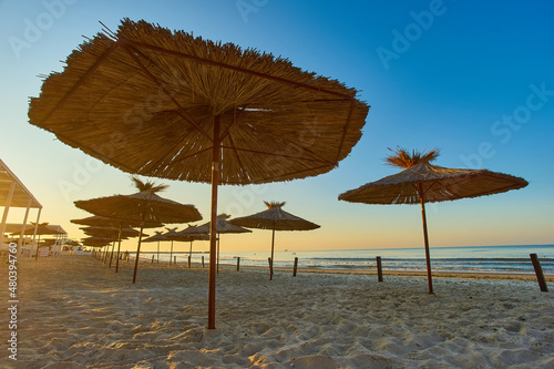 Fototapeta Naklejka Na Ścianę i Meble -  Dawn on the beach. Sun loungers and umbrellas in the rays of the rising sun.