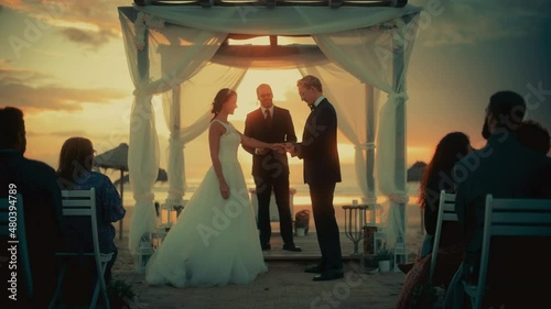 Beautiful Bride and Groom During an Outdoors Wedding Ceremony on an Ocean Beach at Sunset. Perfect Venue for Romantic Couple to Get Married, Exchange Rings, Kiss and Share Celebrations with Friends.
