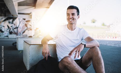 Cheerful man sitting on street skate park