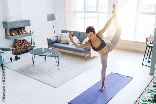 Young woman doing yoga in bright room
