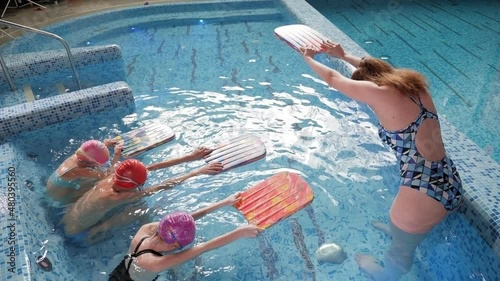 Three children learn to swim and dive in the pool together with a coach. Group of children on a swimming class.