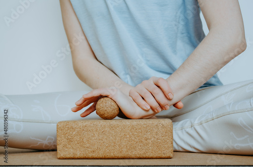Front view close up of person doing palmar fascia release with a small cork ball on a cork block. Concept: self care practices at home, SMFR, sustainable, eco friendly props