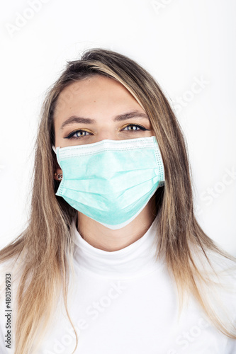 Healthcare and medicine concept. Close up young and long hair brunette woman portrait with medicine mask on her face isolated on white background. Golden makeup and wearing white sweater