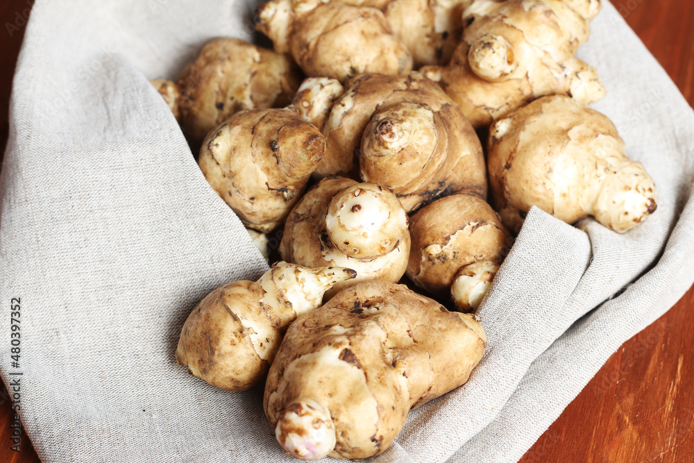 Raw Jerusalem artichoke on a gray linen cotton napkin. Jerusalem artichoke solar root, earthen pear. Raw Jerusalem artichoke on a gray linen cotton napkin. Jerusalem artichoke solar root, earthen pear.