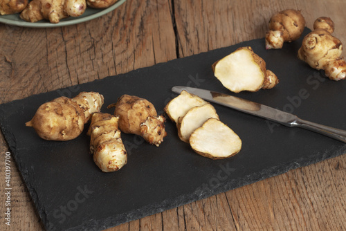 Raw Jerusalem artichokes on the surface of black slate. Healthy food concept