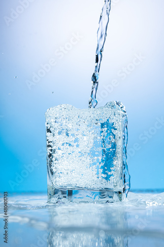 splash of water in a transparent glass on a blue background
