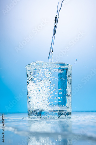 splash of water in a transparent glass on a blue background