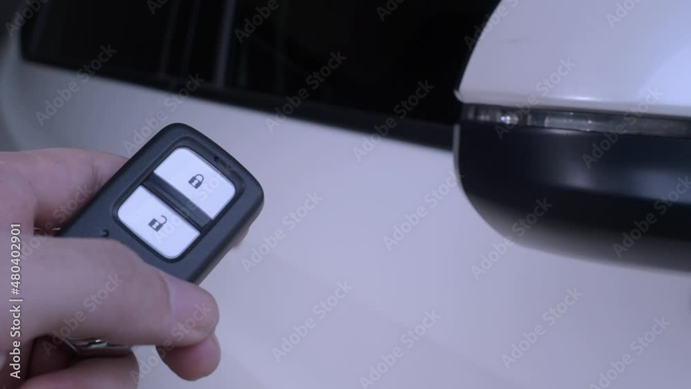Car key remote control. Locking and unlocking the car by the car key remote control. Pressing the button of the car key and the lights blink when door opens or closed. Man hand using remote key. Car key remote control. Locking and unlocking the car by the car key remote control. Pressing the button of the car key and the lights blink when door opens or closed. Man hand using remote key.