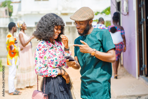 excited african guy and a lady with smart phone- outdoor communication concept