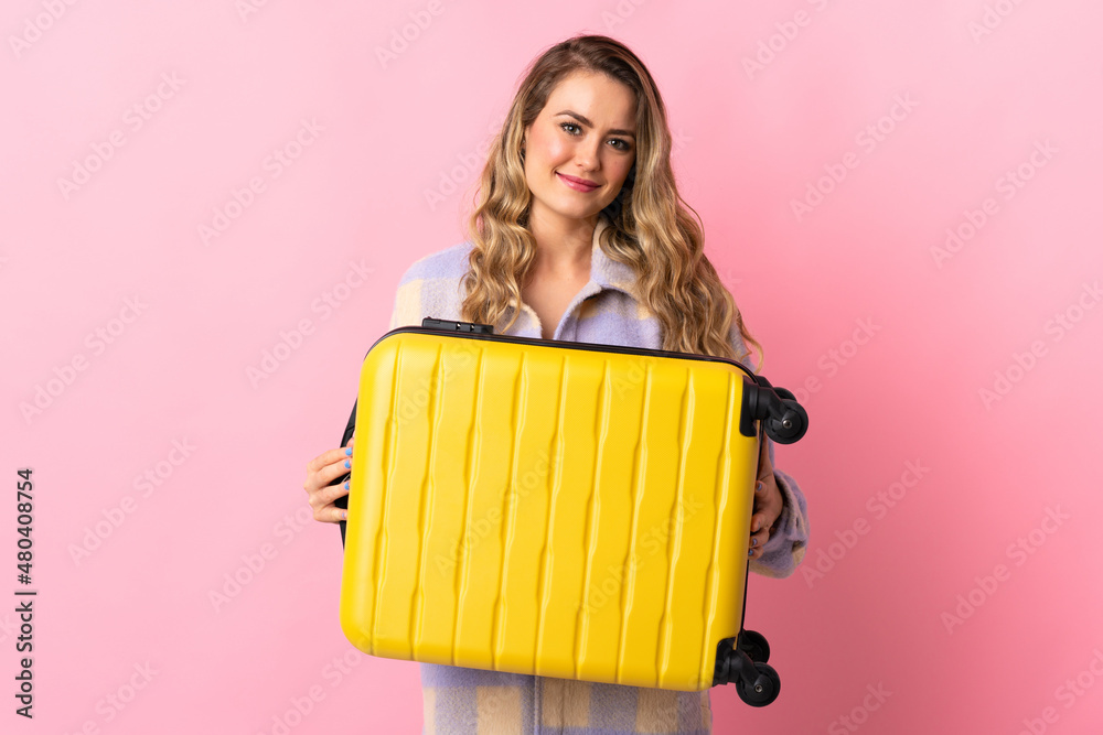 Young Brazilian woman isolated on pink background in vacation with travel suitcase Young Brazilian woman isolated on pink background in vacation with travel suitcase