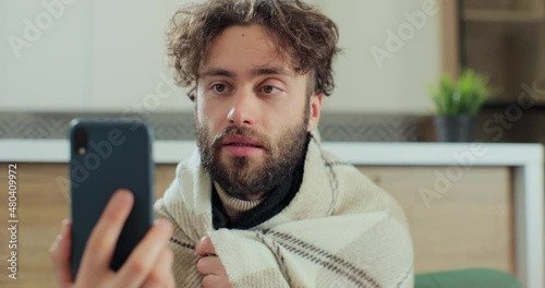 Man with running nose, caughing having video call with doctor while staying at home. Patient video conferencing with general practitioner on smartphone. photo