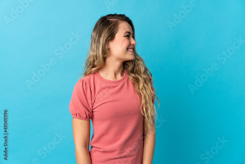 Young Brazilian woman isolated on blue background looking side © luismolinero