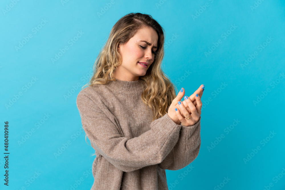Young Brazilian woman isolated on blue background suffering from pain in hands Young Brazilian woman isolated on blue background suffering from pain in hands