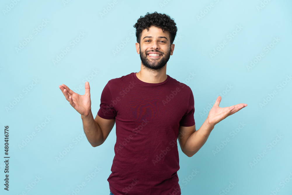 Young Moroccan man isolated on blue background smiling a lot Young Moroccan man isolated on blue background smiling a lot