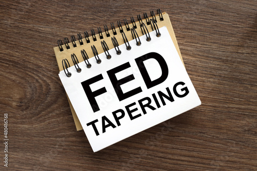 FED TAPERING. two notebooks with a spring on a wooden background