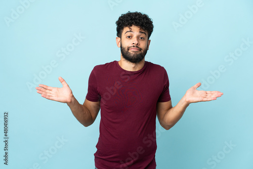 фотографія Young Moroccan man isolated on blue background making doubts gesture