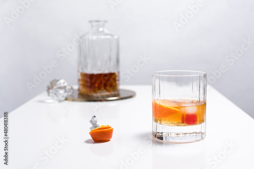 Fototapeta Naklejka Na Ścianę i Meble -  Vaso de vermut con hielo decorado con cerezas, rodajas de naranja y decantador sobre mesa blanca	