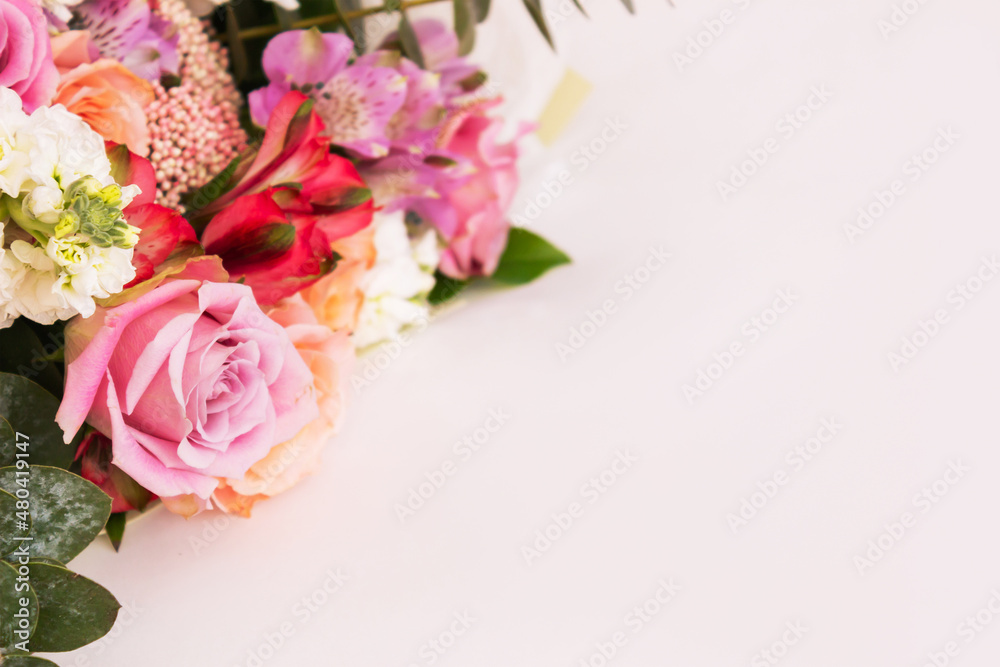 A bouquet of colorful pink and orange roses on a white table. Flowers, spring. Floral background. Empty copy space for text or design