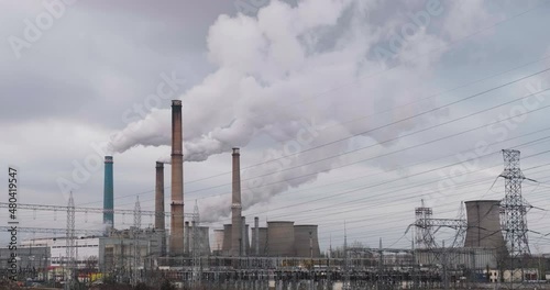 Bucharest South Power Station (CET Sud) in the evening, a large thermal power plant with cooling towers emitting fumes in the air, on overcast Winter day.