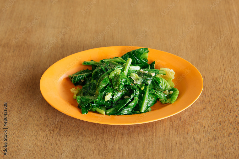 Fried Kai Lan Oyster Sauce with fried garlic (Chinese Broccoli) on wooden background top view food Fried Kai Lan Oyster Sauce with fried garlic (Chinese Broccoli) on wooden background top view food