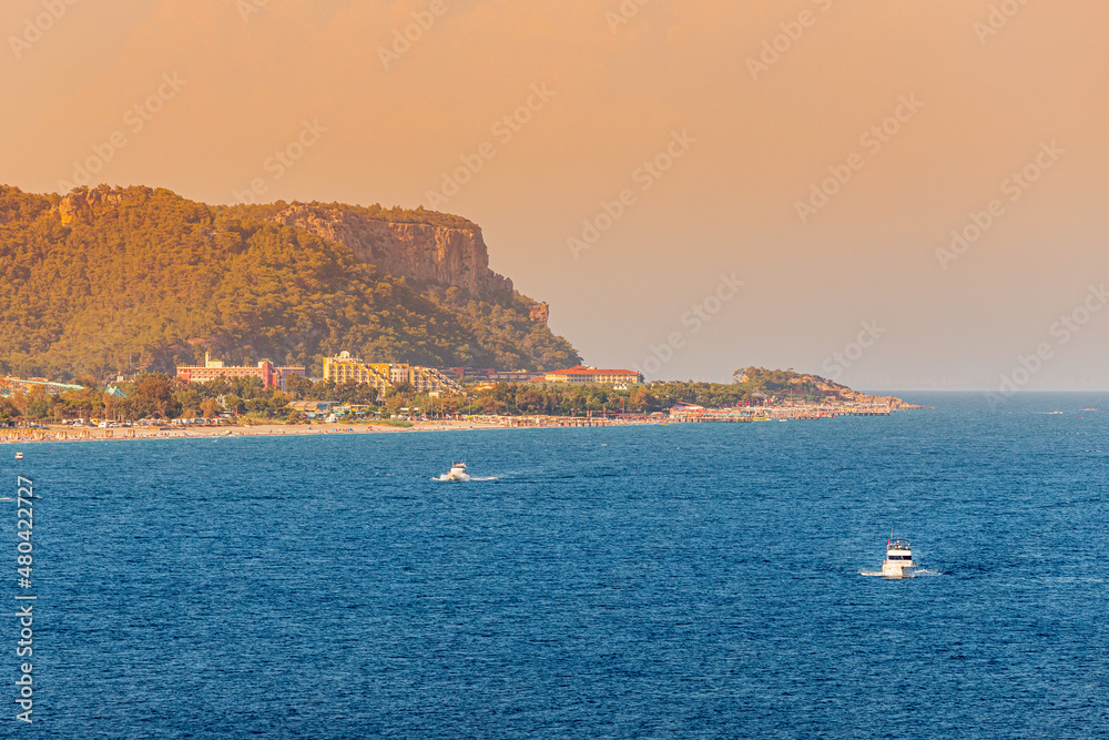 Sunset view of the resort village of Camyuva in Turkey with small boats sailing in the sea