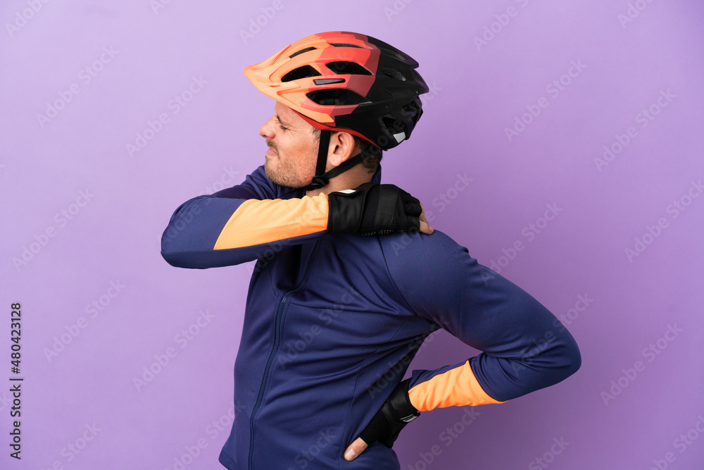 Young Brazilian cyclist man isolated on purple background suffering from pain in shoulder for having made an effort Young Brazilian cyclist man isolated on purple background suffering from pain in shoulder for having made an effort