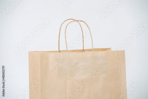 Cropped image of empty brown paper bag with rope handles over white background