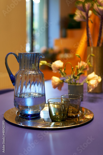 Jug on the tray on very peri table with two glasses