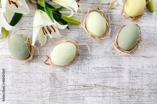 Photography White lilies and easter eggs on wooden background, copy space.