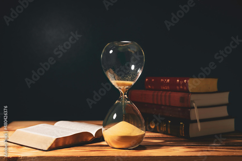 Vintage hourglass with open Bible photo