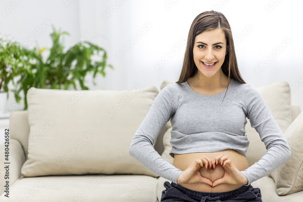 Photo of pregnant woman making heart shape with hands.