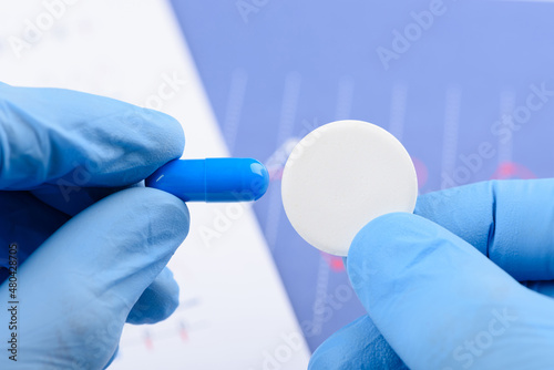 Scientist hold in hands and compare big carbon effervescent pill and small blue capsule