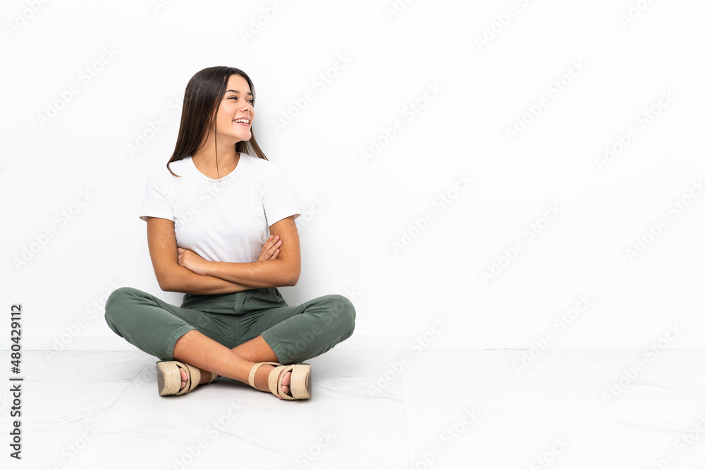 Teenager girl sitting on the floor happy and smiling