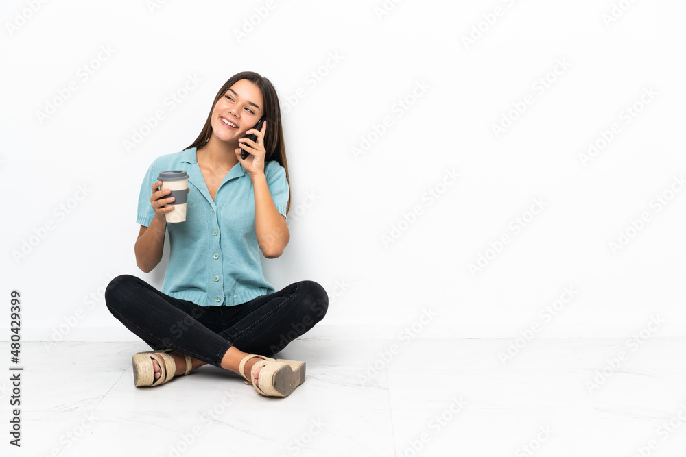 Teenager girl sitting on the floor holding coffee to take away and a mobile Teenager girl sitting on the floor holding coffee to take away and a mobile