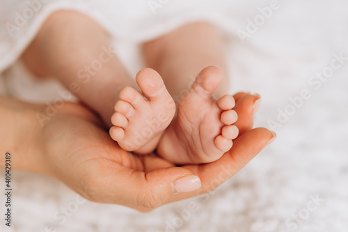 Baby feet in mother's hands. Mom and her child. Happy family concept. Beautiful concept image of motherhood