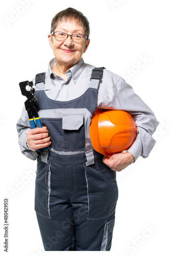 an elderly woman, a grandmother, a worker in special clothes, holds a helmet in one hand, holds a tool in the other hand. Woman, grandmother smiles and looks at us. isolated.