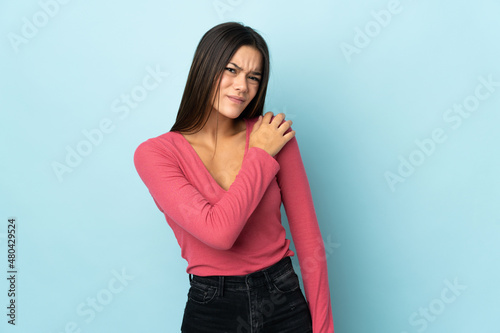 Teenager girl isolated on blue background suffering from pain in shoulder for having made an effort