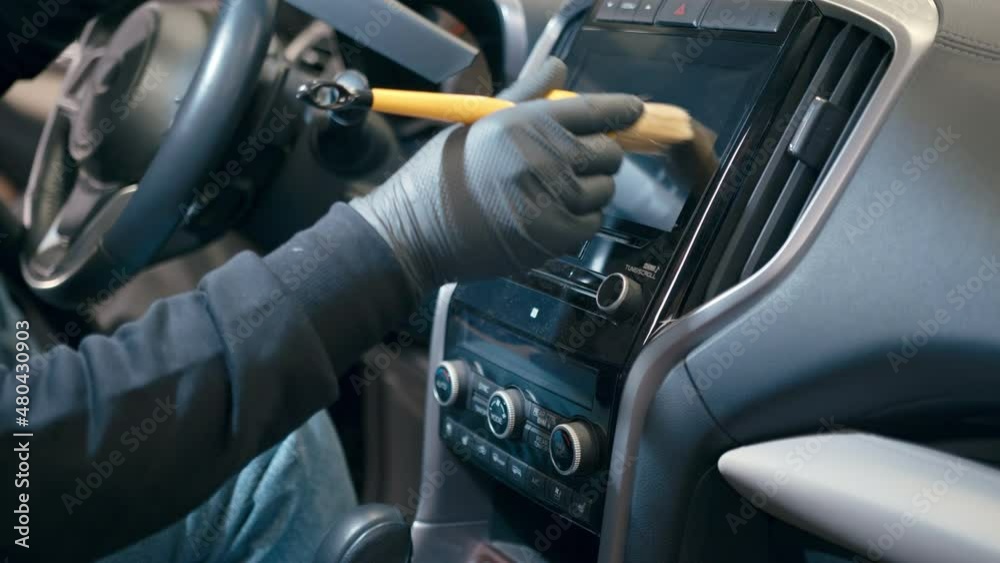 Close up of worker hand cleaning auto interior with special brush from dust, close up. Car detailing or premium car wash