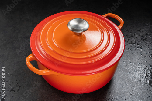 orange dutch oven on wet black surface.